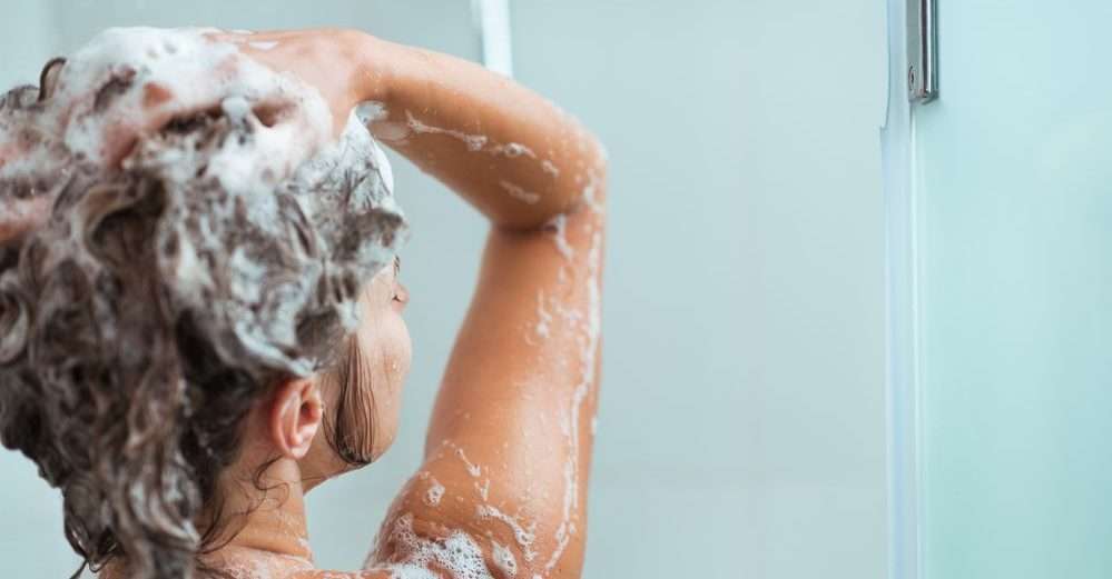 Donna mentre si fa lo shampoo sotto la doccia