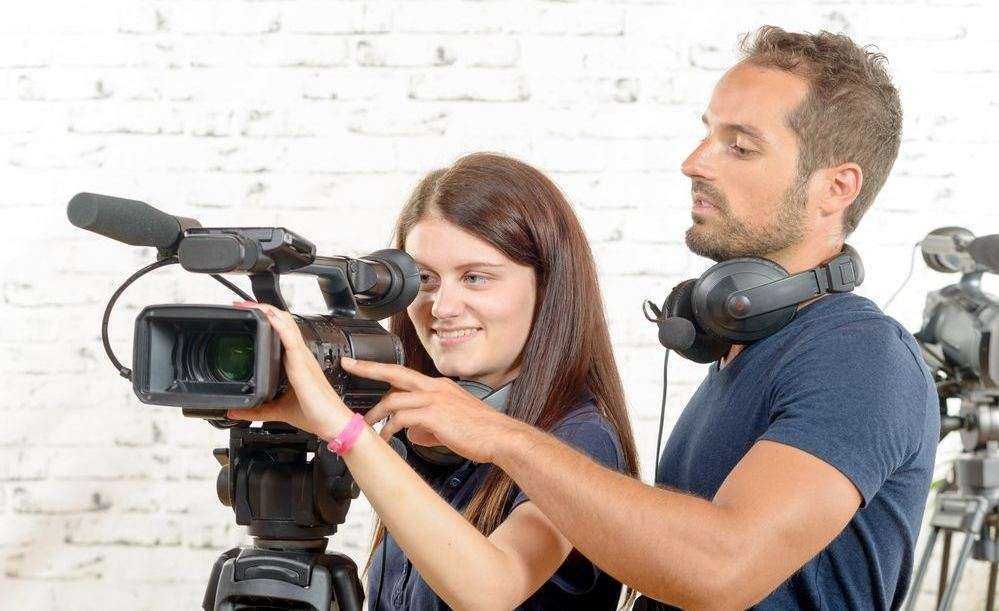 giovane coppia di cameraman alle prese con una videocamera professionale