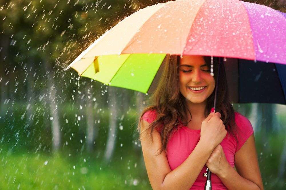 ragazza al riparo dalla pioggia con un ombrello antivento pieghevole a trama di arcobaleno
