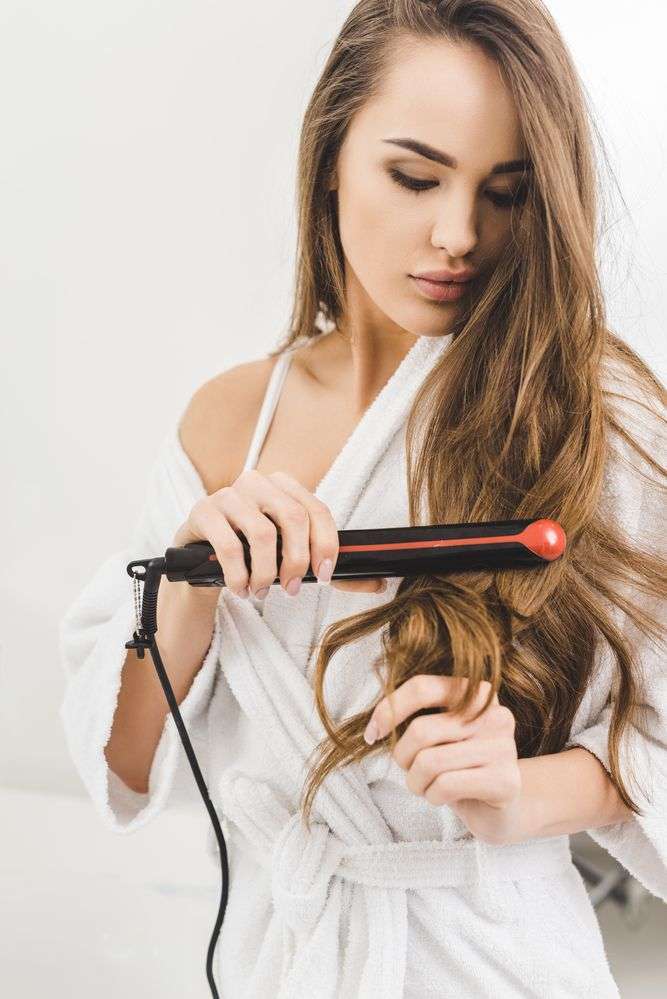 giovane ragazza mentre usa una piastra per capelli professionale
